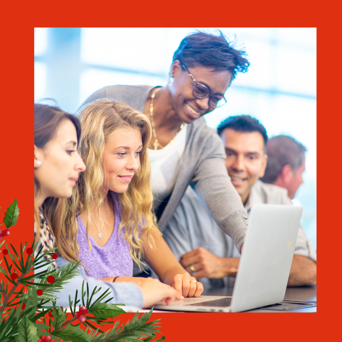 An image on a red background of a woman with glasses, leaning over the shoulders of a group of people sat around a laptop. There is holly and red berries in the left hand corner of the image. 