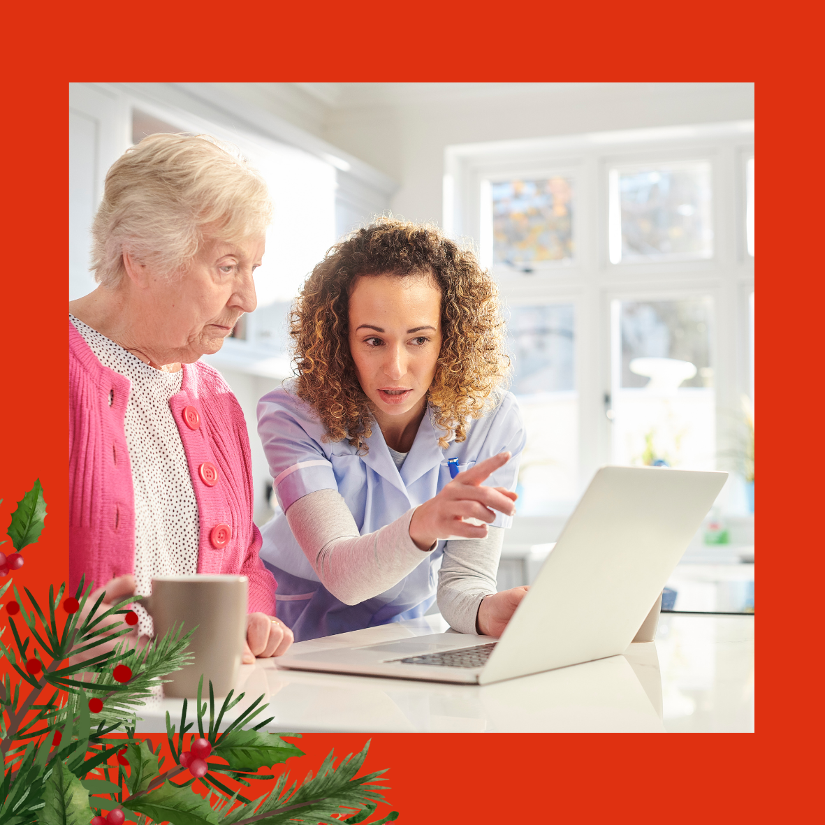 An image of a woman in a blue tunic, showing an elderly lady in a pink cardigan, something on a laptop. There is holly and red berries in the left hand corner of the image.