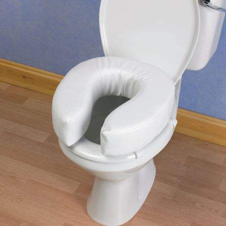 A white padded cushioned seat, placed onto a regular toilet seat.