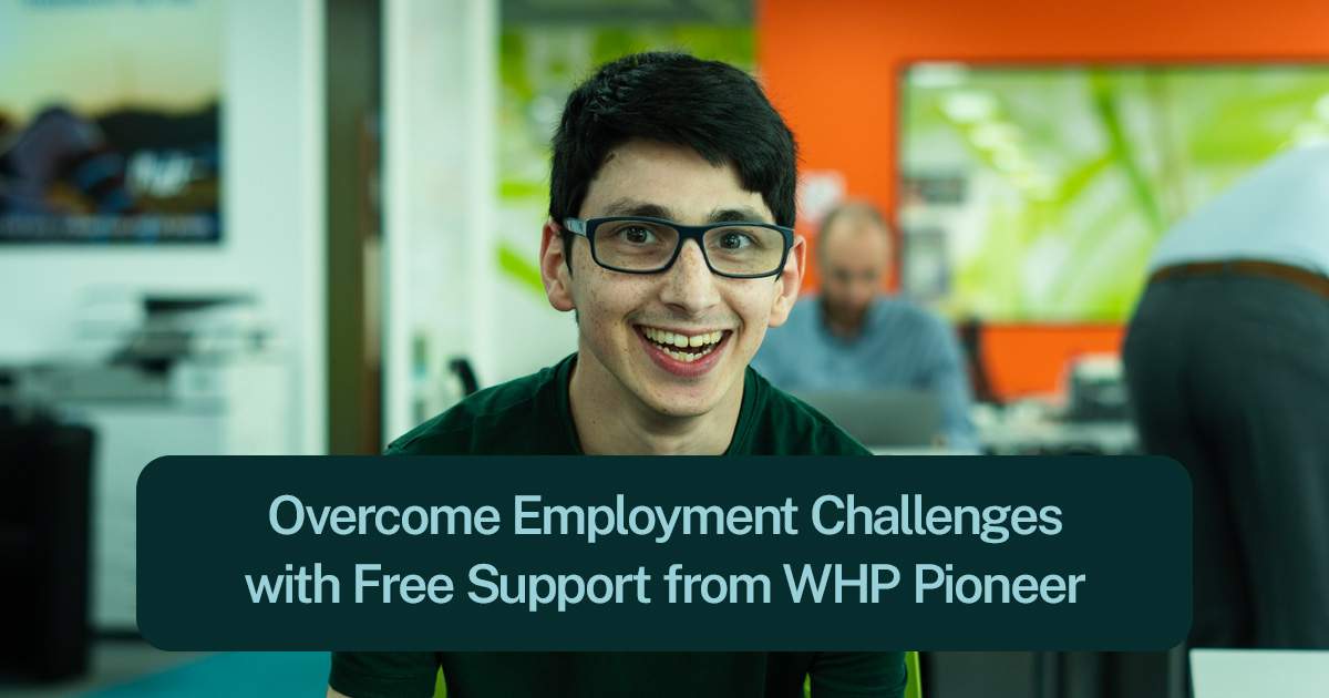 A header image of a young man with dark hair, dark rimmed glasses and freckles. He is smiling with his mouth wide, showing his teeth. Behind him there is a blurry image of a man sat at a desk in an office. There are the words, overcome employment challenges with free support from WHP Pioneer.