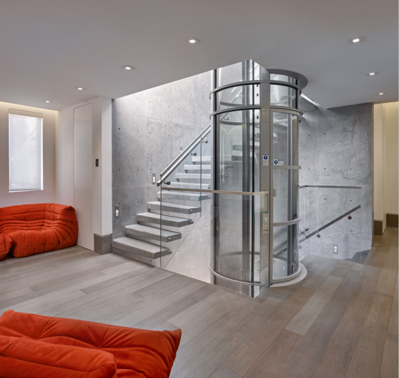 cylindrical lift nest to a set of stairs coming into a living room 