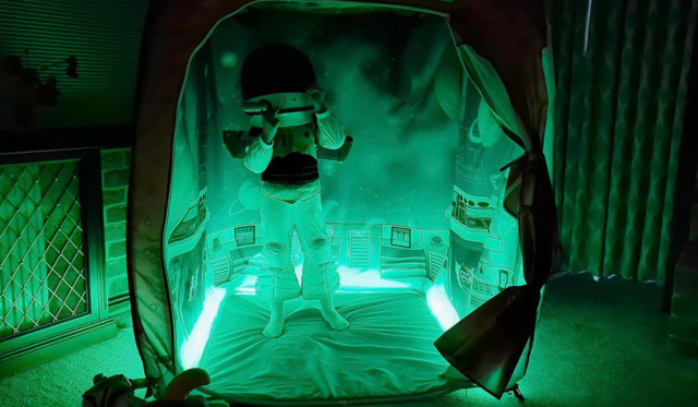 Child dressed as astronaut in space themed pod with green lighting