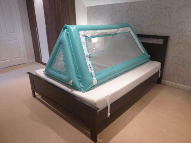Safe place bed inflated with side door zipped up on top of regular bed