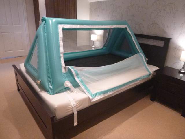 Safe place bed inflated with side door unzipped on top of regular bed