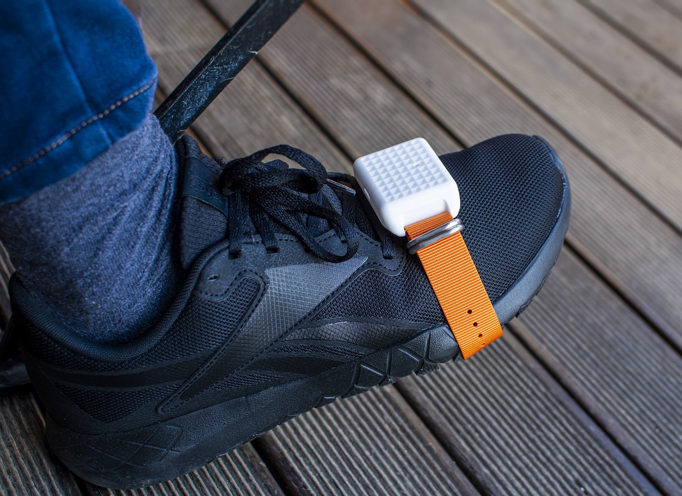 Featherlight mouse on a persons shoe secured by an orange strap.