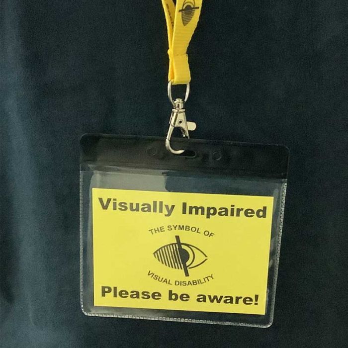 Yellow lanyard with plastic case containing card with Visually impaired please be aware text, with strap