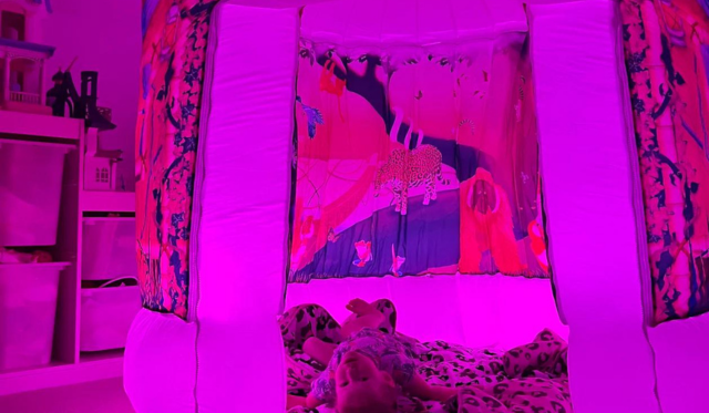 Child laying in jungle themed pod with purple lighting