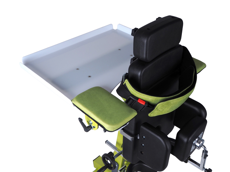 Green frame COCO stander with black cushioning in upright position with tray attached.